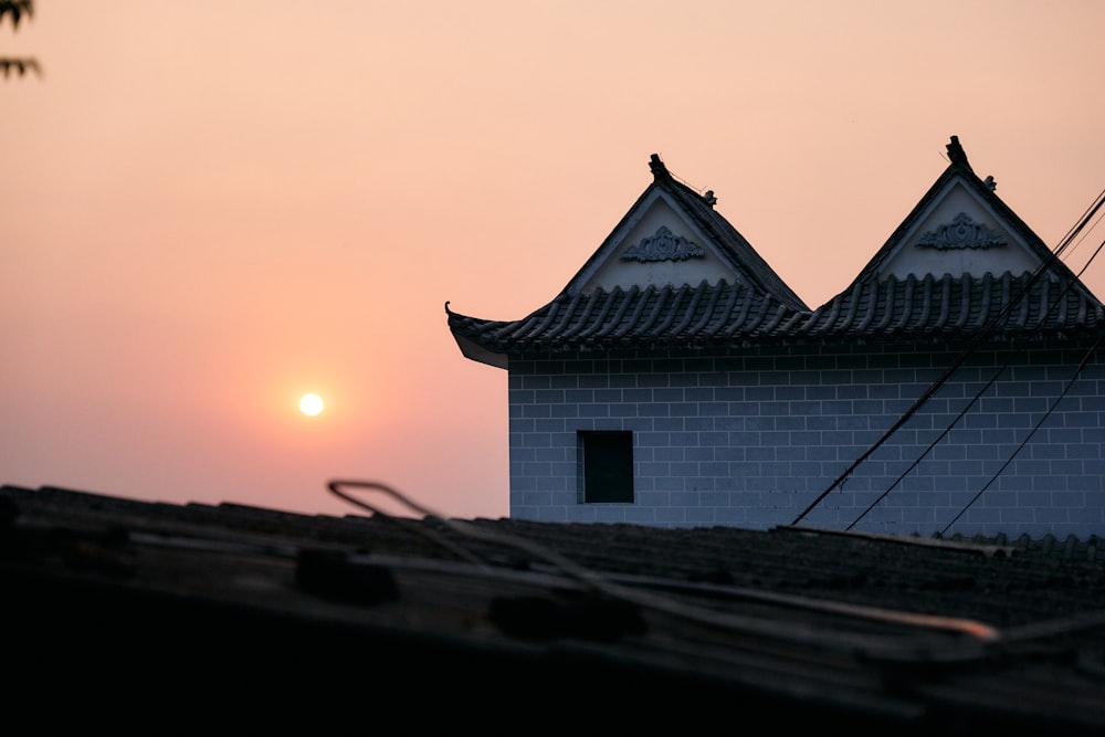 the sun is setting behind the roof of a building