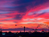 Sunset casting warm hues over a bustling amusement park with colorful rides.