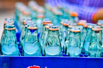 Quality control technician inspecting glass bottles under bright factory lights.
