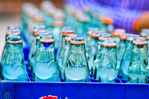 Close-up of clear medical alcohol bottles lined up in a clean manufacturing facility.
