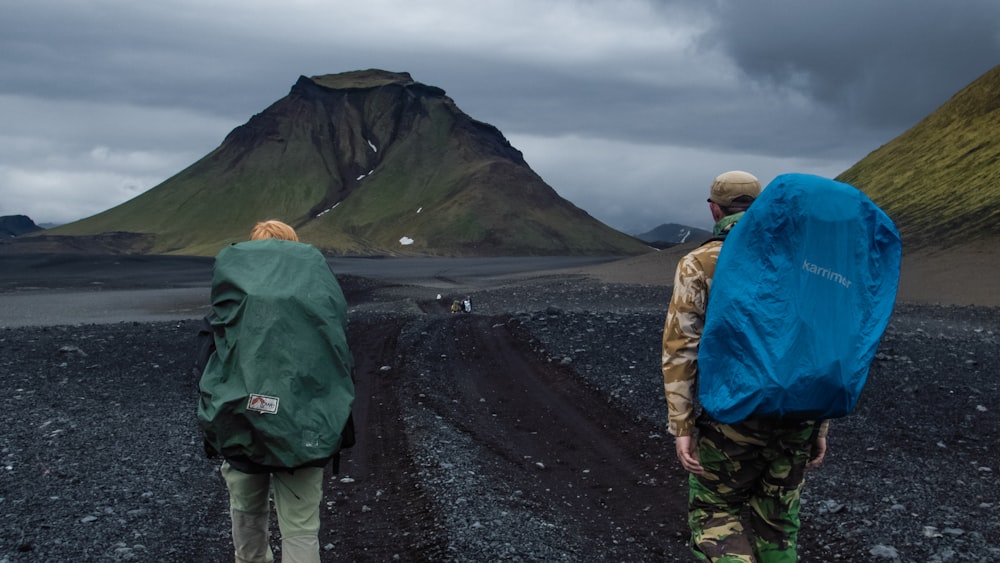 a couple of people walking across a dirt road