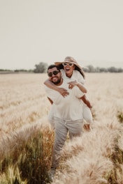 a man carrying a woman on his back through a wheat field