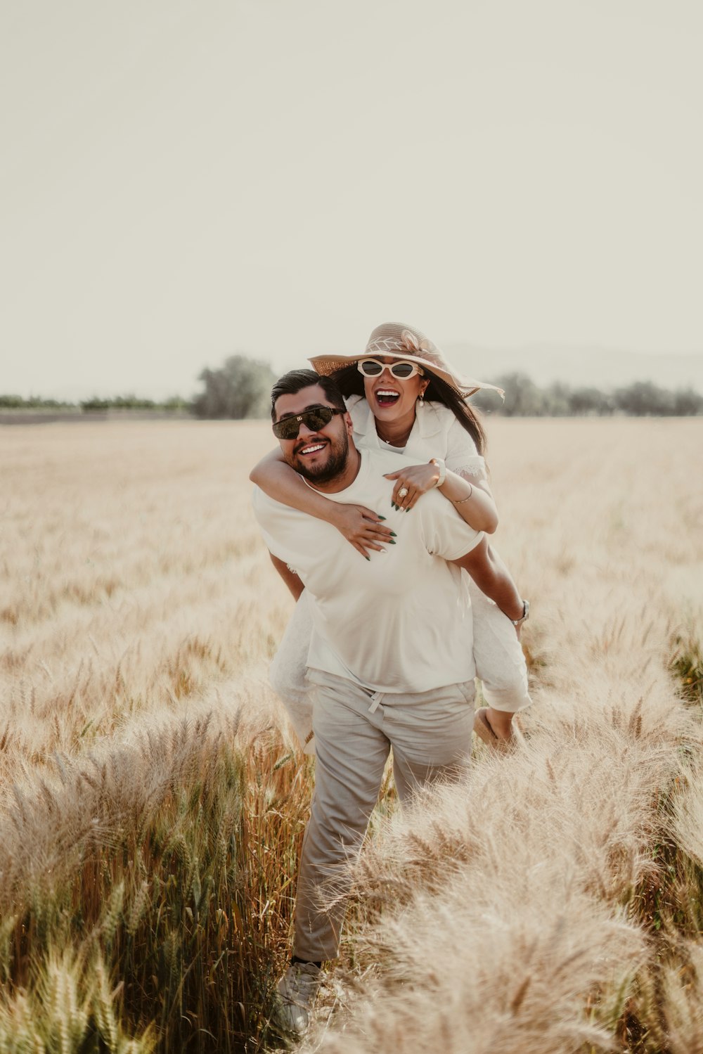a man carrying a woman on his back through a wheat field