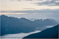 A panoramic view of a misty mountain range under soft blue skies.