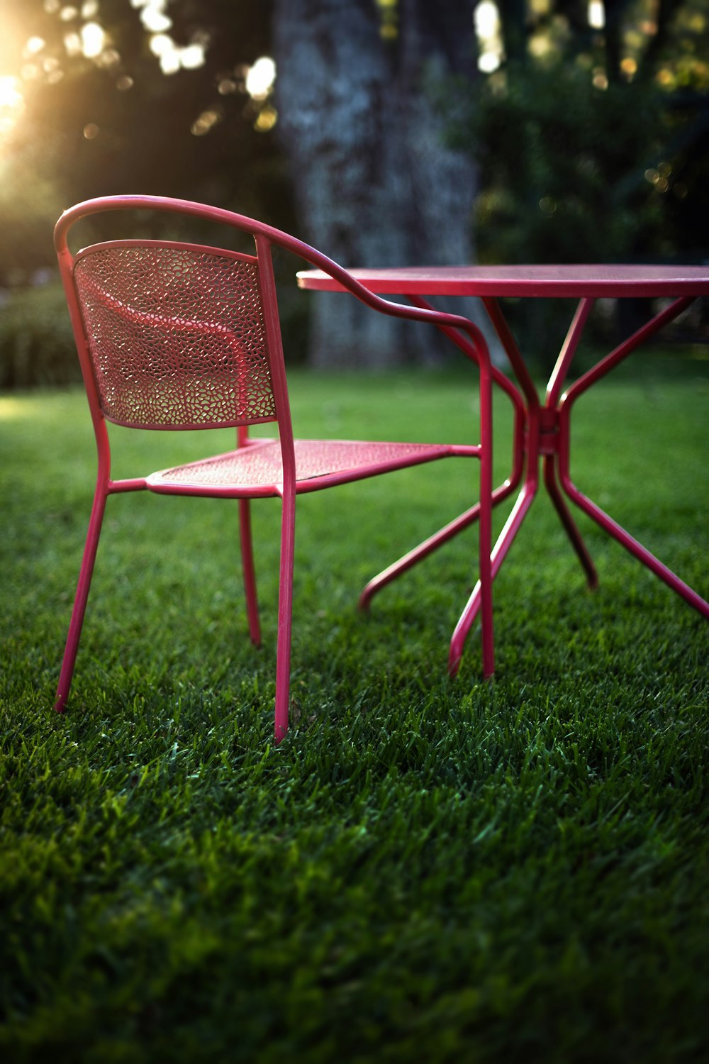 Una mesa y una silla rojas sentadas en la parte superior de un exuberante campo verde