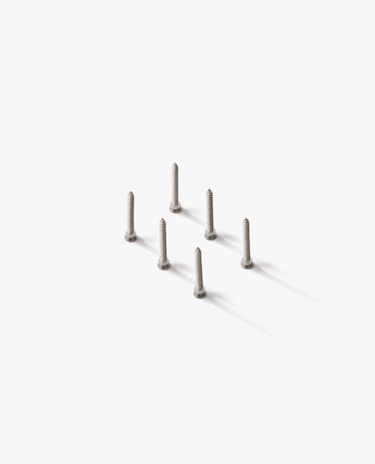 Seven silver screws are neatly arranged in a hexagonal pattern on a white surface, casting soft shadows.