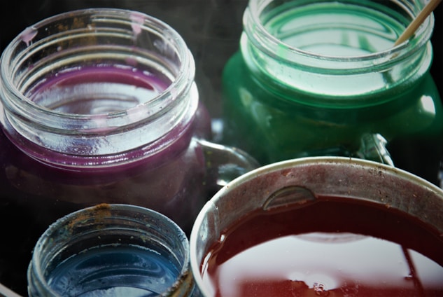 A colorful assortment of vibrant slime jars arranged on a wooden table, glowing softly under warm light.