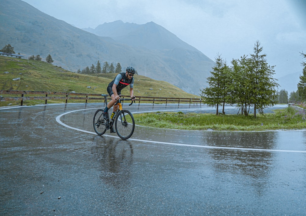 a man riding a bike down a rain soaked road