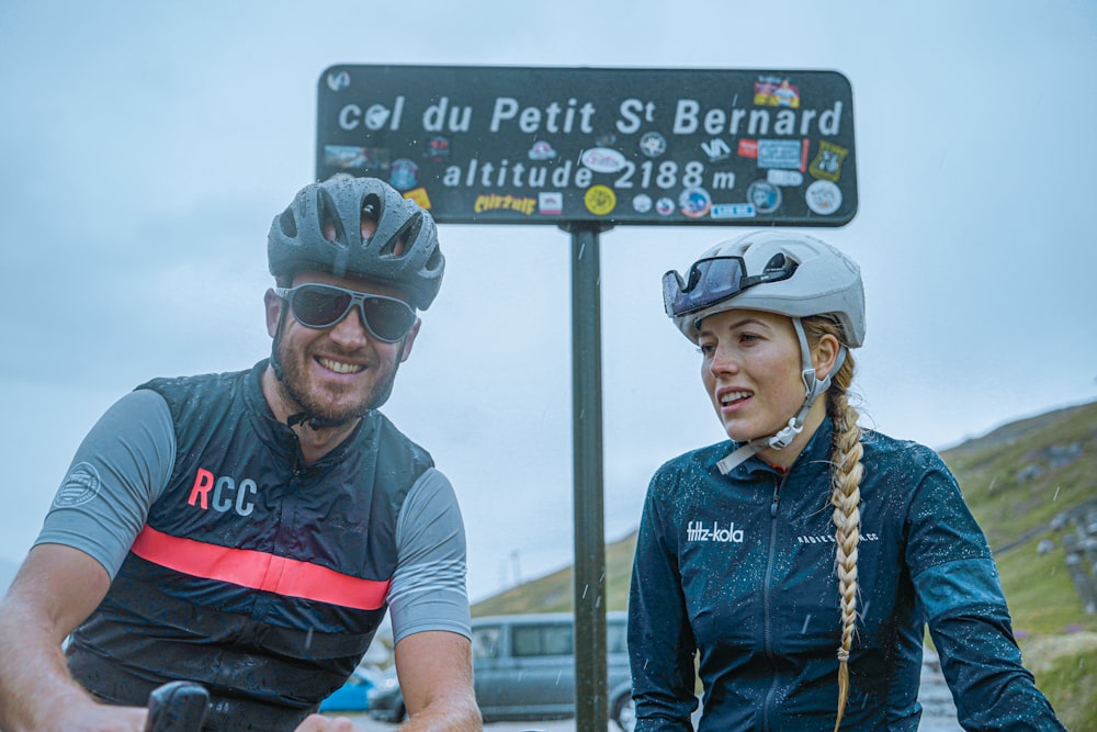 a man and a woman riding bikes next to a street sign