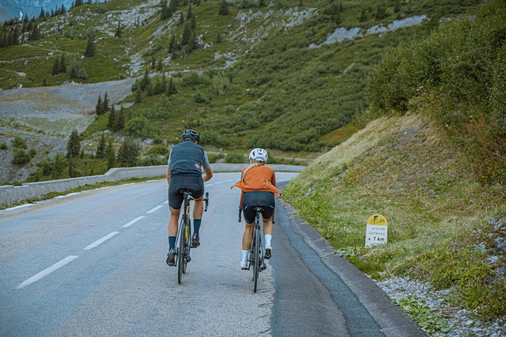 a couple of people riding bikes down a road