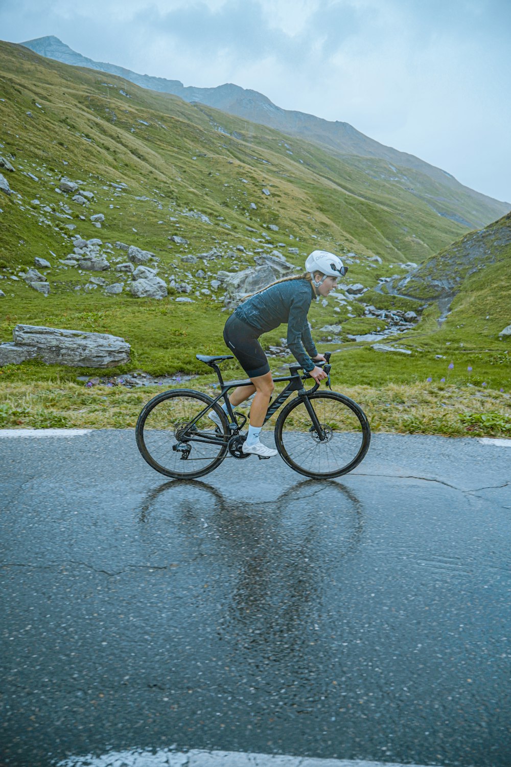 a man riding a bike down a rain soaked road