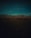 Rolling hills under a twilight sky with a solitary figure tending to a herd of animals in the foreground. The landscape is dimly lit, accentuated by the shadows that stretch across the terrain.