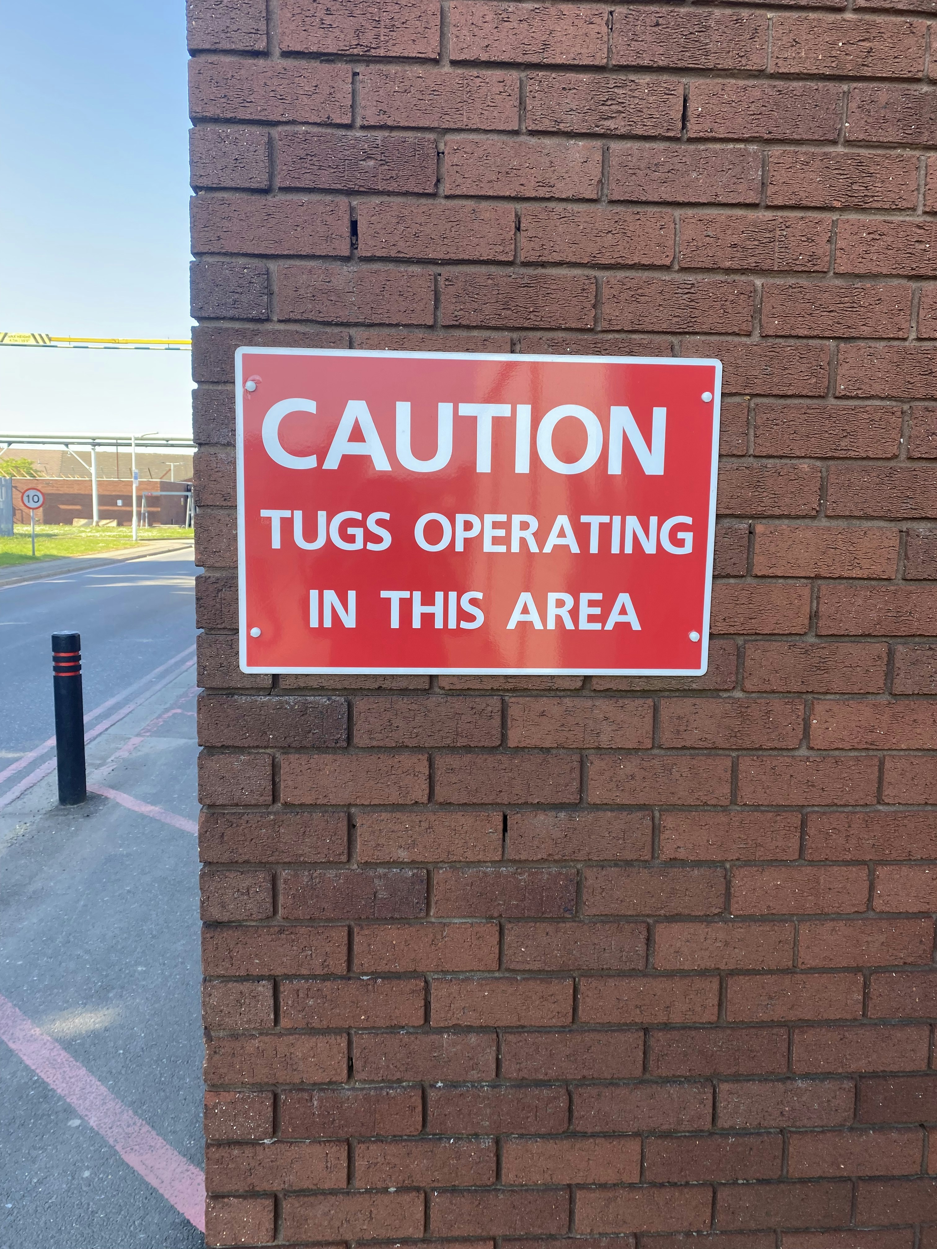 A red sign on a brick wall that says caution tug operating in this area ...
