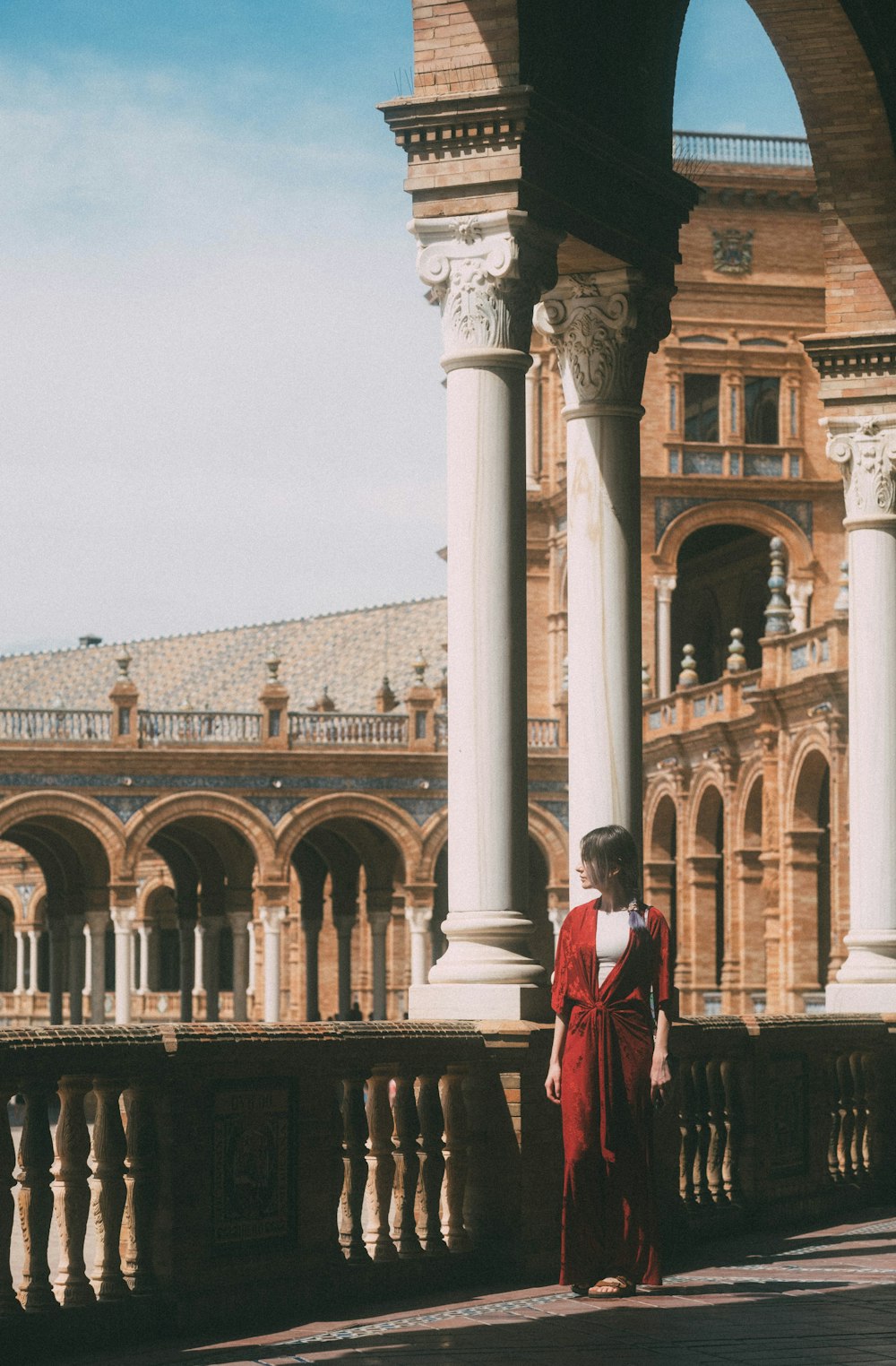 a woman in a red dress standing on a balcony