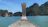 Small boat gliding over calm turquoise waters with jungle cliffs in the distance under a sunny sky.