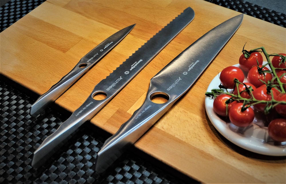 a couple of knives sitting on top of a wooden cutting board