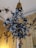 A decorative floral arrangement is hanging from the ceiling, featuring intricately designed white roses with green leaves set against a lavish, ornately decorated background. The background has golden hues with additional floral motifs, enhancing the luxurious ambiance.