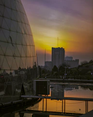 A modern urban development with sleek glass buildings reflecting the sunset.