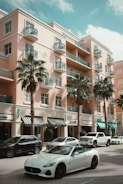 a white sports car parked in front of a pink building