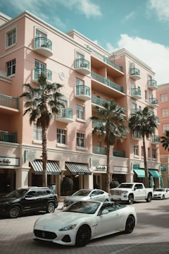 a white sports car parked in front of a pink building