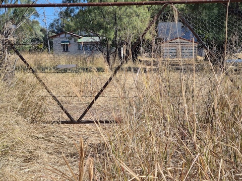 Rustic metal gate installed at a countryside home entrance.