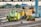 Numerous maintenance vehicles and equipment are stationed on railway tracks. The area appears to be an industrial or depot setting with multiple rail lines converging. Various colors of machinery, predominantly yellow and green, are visible, and some construction or maintenance materials are scattered nearby.