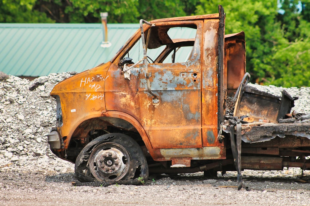 an old rusted truck sitting on top of a pile of rubble