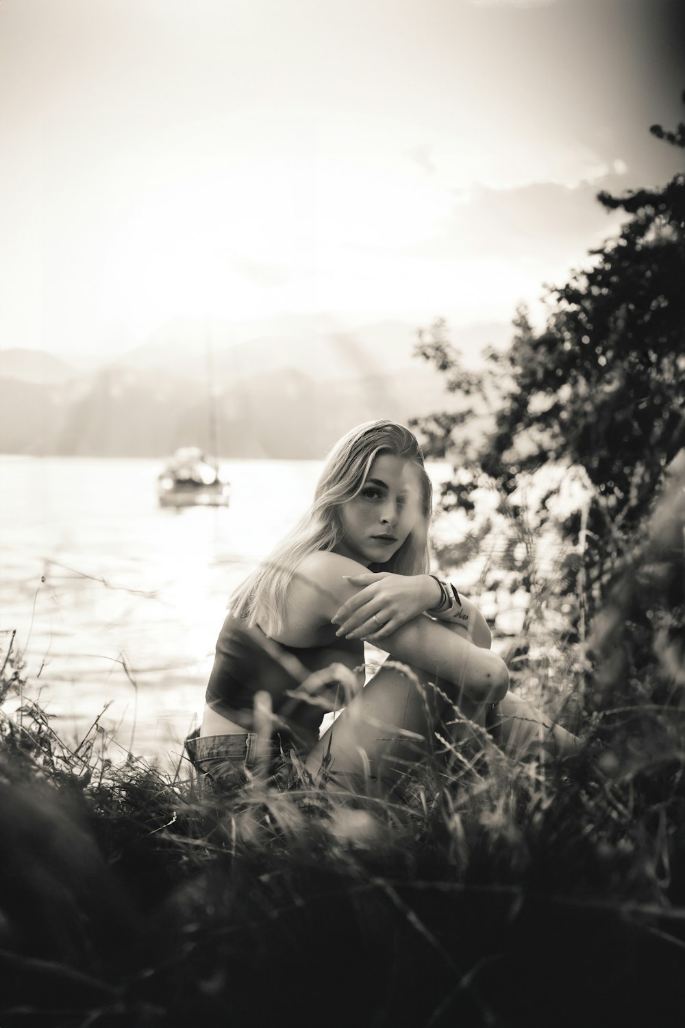 a young girl sitting on the shore of a lake