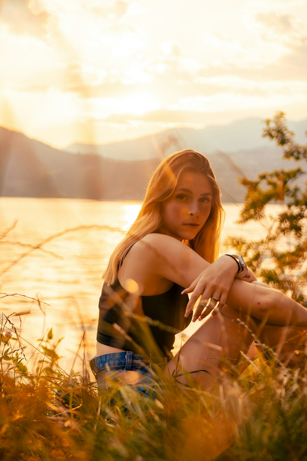 a woman sitting on the ground next to a body of water