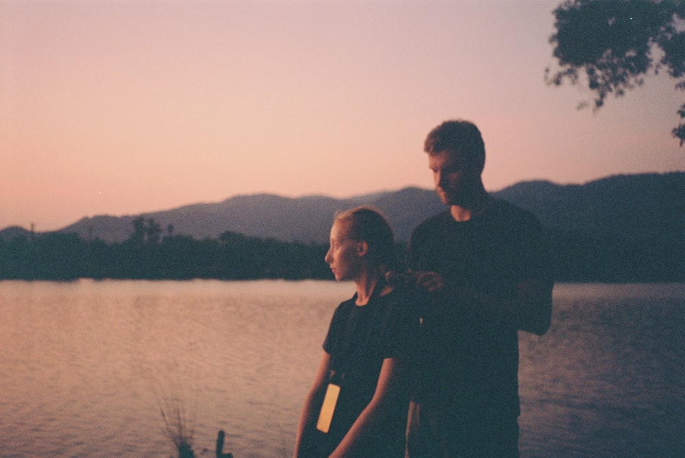 a man and a woman standing next to a body of water