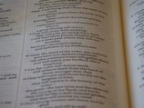 An open book with text printed in two columns. The text appears to be in a poetic format with indented lines and is focused on a religious or spiritual theme. The pages show chapter and verse numbers, indicating scriptural content.