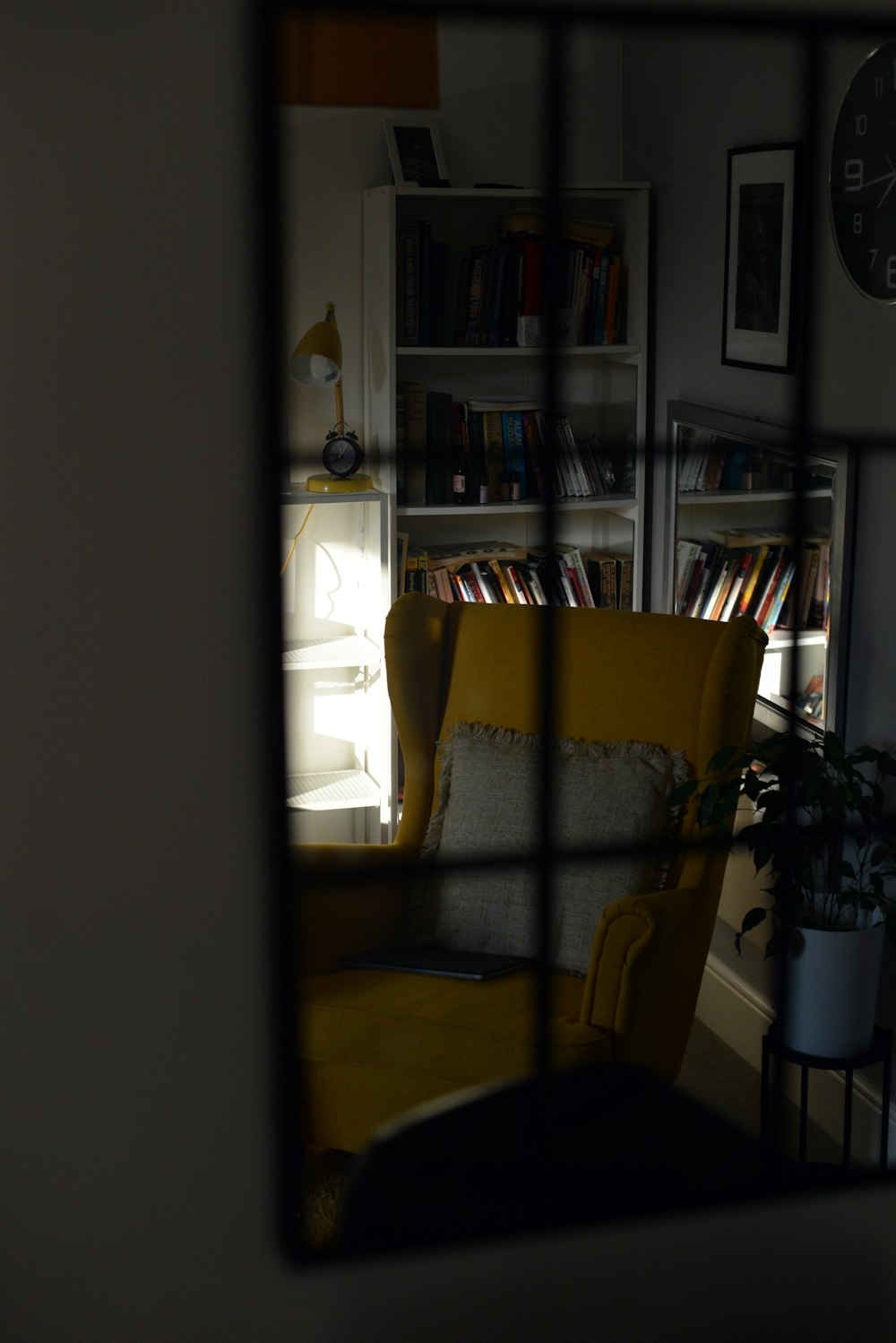 Una silla amarilla sentada en una sala de estar junto a un estante de libros