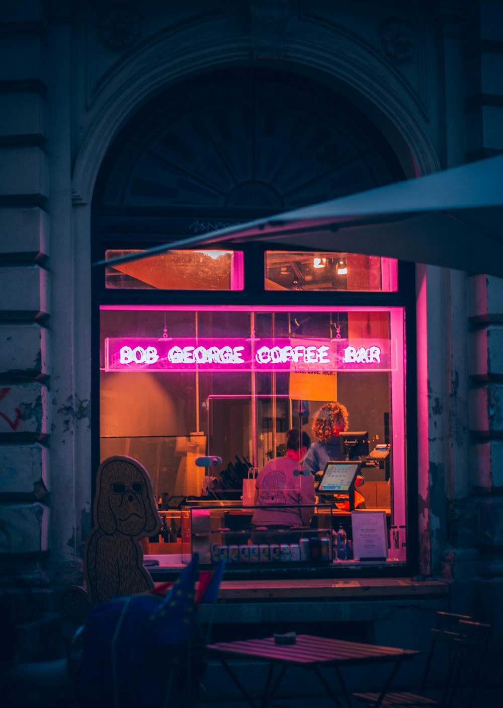 a person sitting at a table in front of a coffee shop