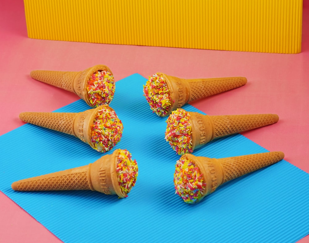 four ice cream cones with sprinkles on a blue mat