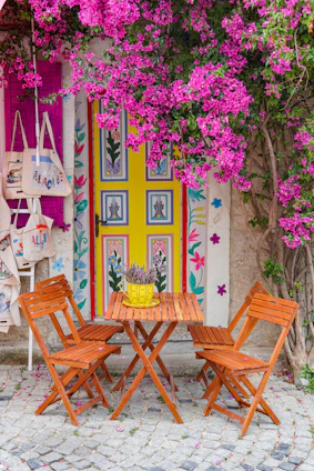 a wooden table with four chairs under a pink bougaia tree Türkiye