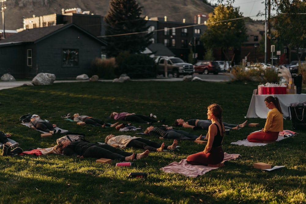 a group of people laying on top of a lush green field