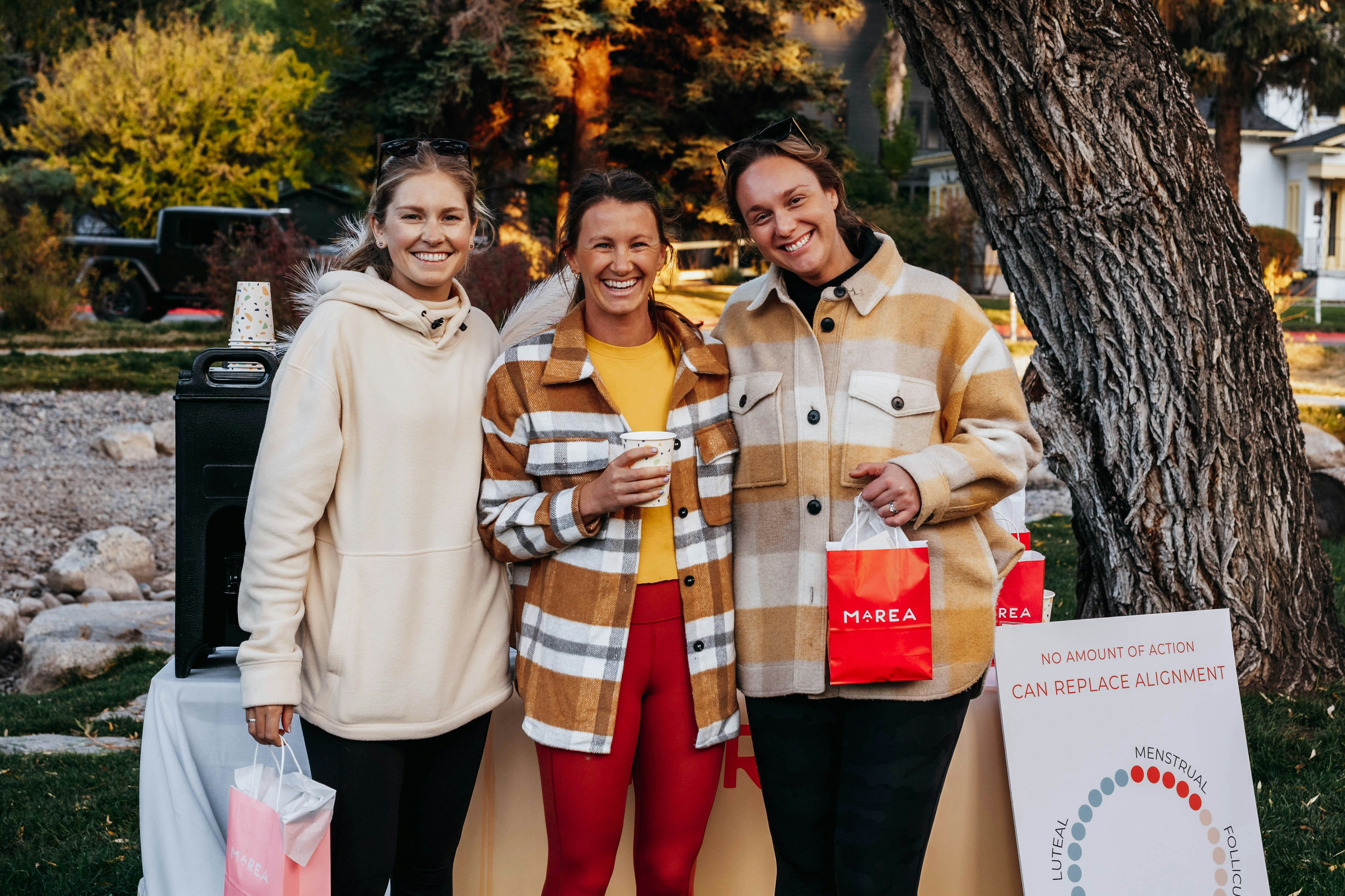 two women standing next to each other near a tree