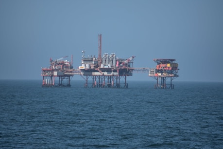 African workers operating on an offshore oil platform under a bright sky.