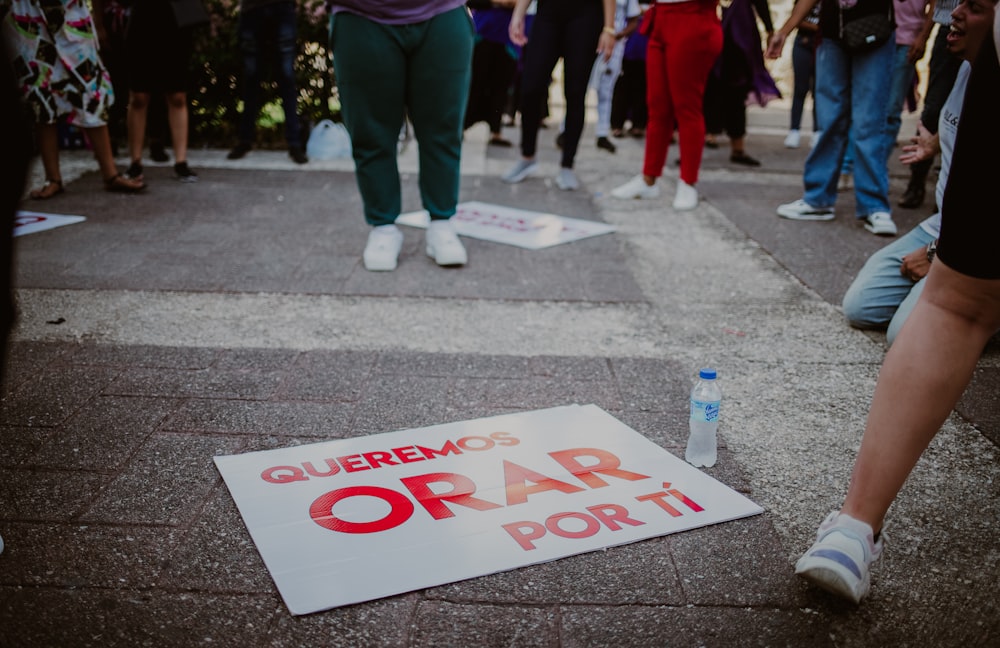 a group of people standing around a sign on the ground