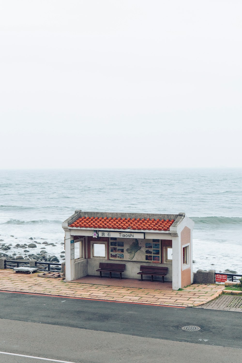 a small building sitting on the side of a road next to the ocean