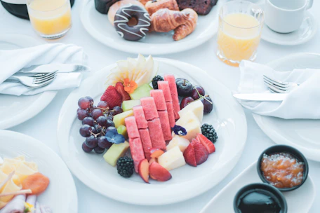 A beautifully arranged breakfast basket with fresh fruits, pastries, and a cup of coffee on a rustic wooden table