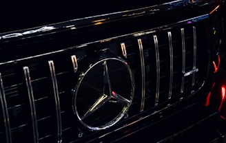 Close-up of a polished chrome grille and emblem on a luxury vehicle under soft lighting.