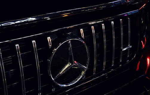 A close-up of a polished car grill with the Winnipeg West Automotive Group logo subtly reflected.