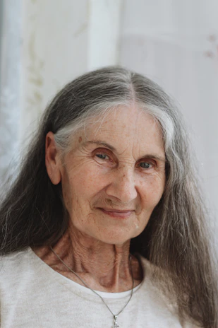 A softly lit photo of Nancy Ellen Long Guthrie smiling gently, framed by desert gold and sage green hues.