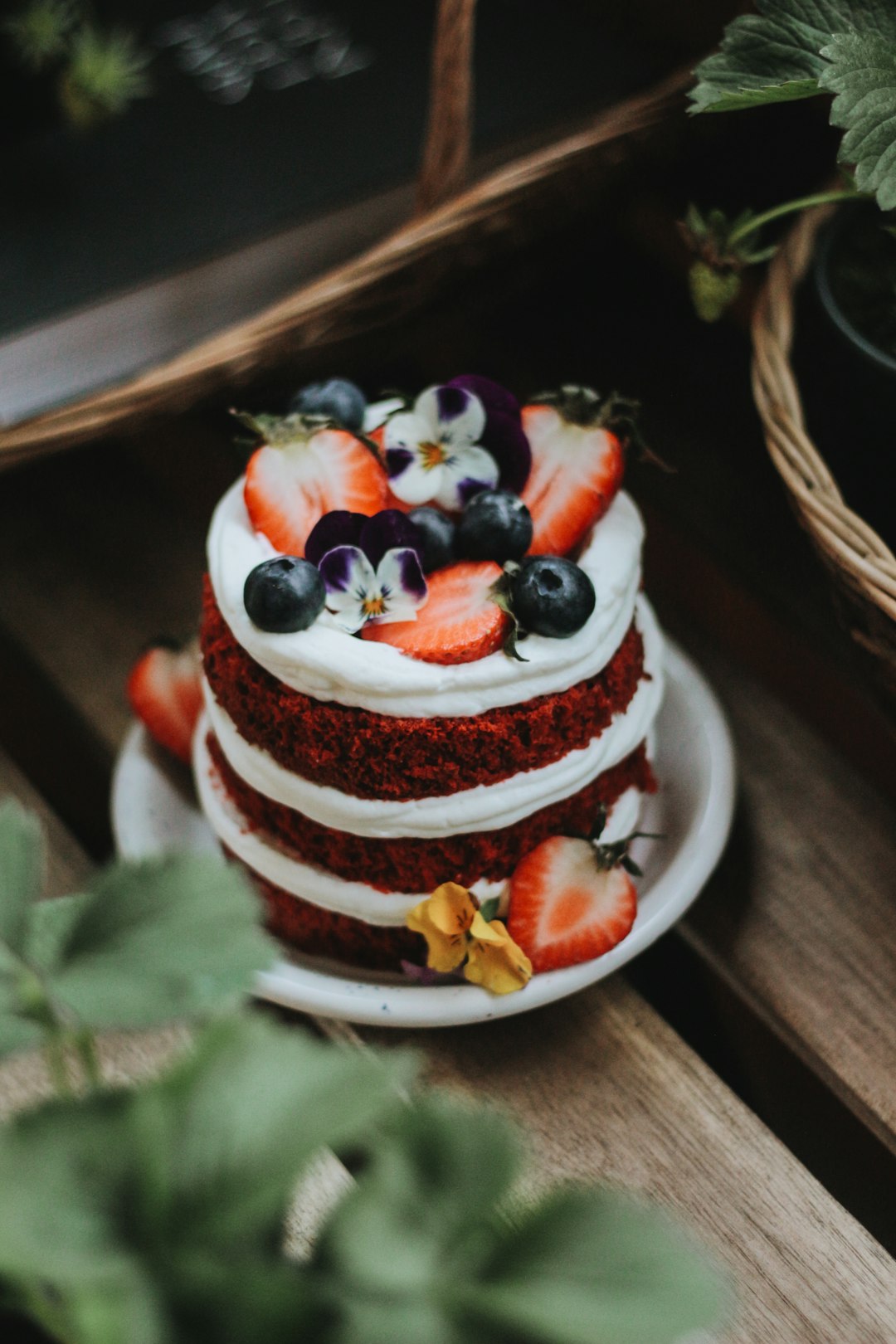 a three layer red velvet cake topped with berries and blueberries