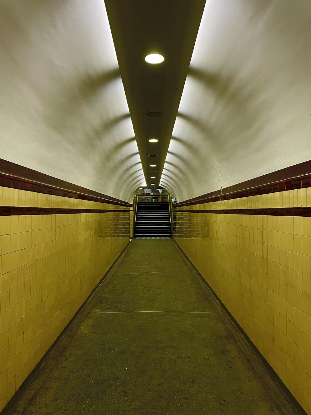 a long hallway with yellow walls and a set of stairs