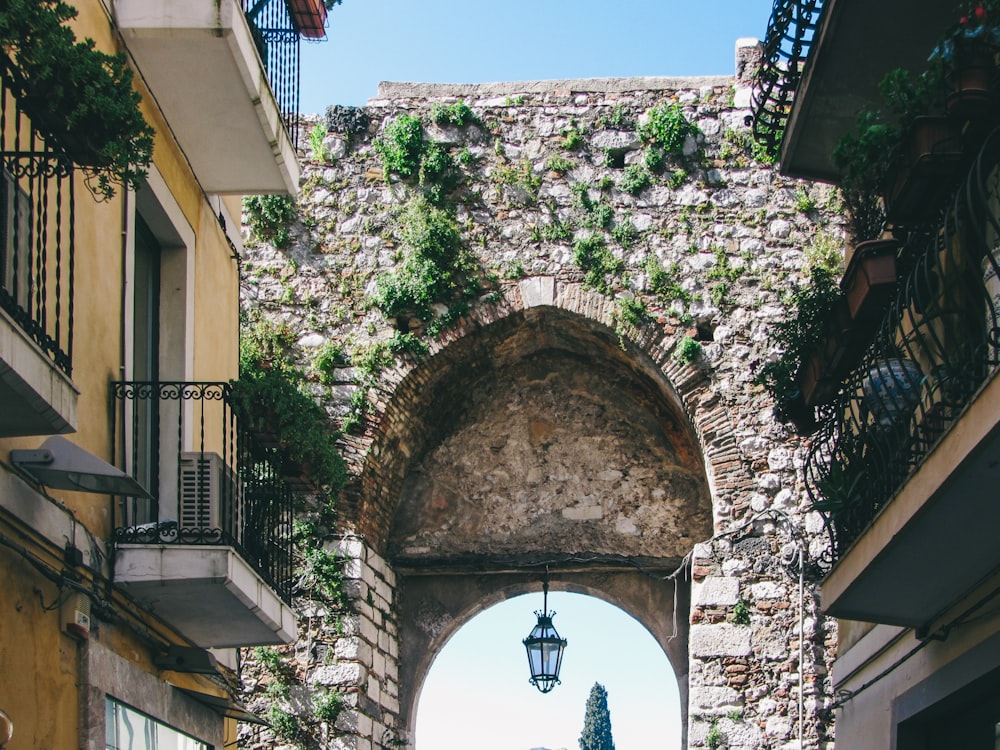 a narrow street with a stone wall and a lamp post