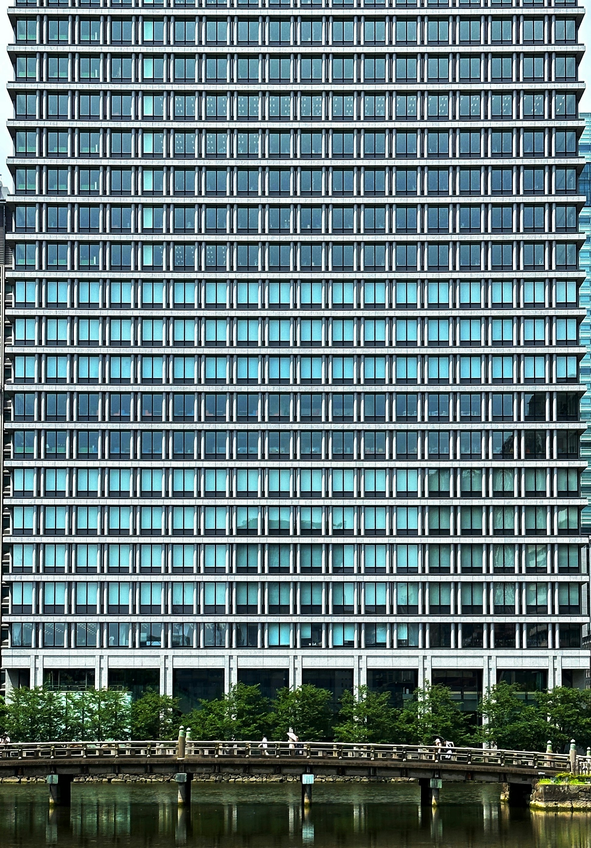 A very tall building with lots of windows next to a body of water photo ...