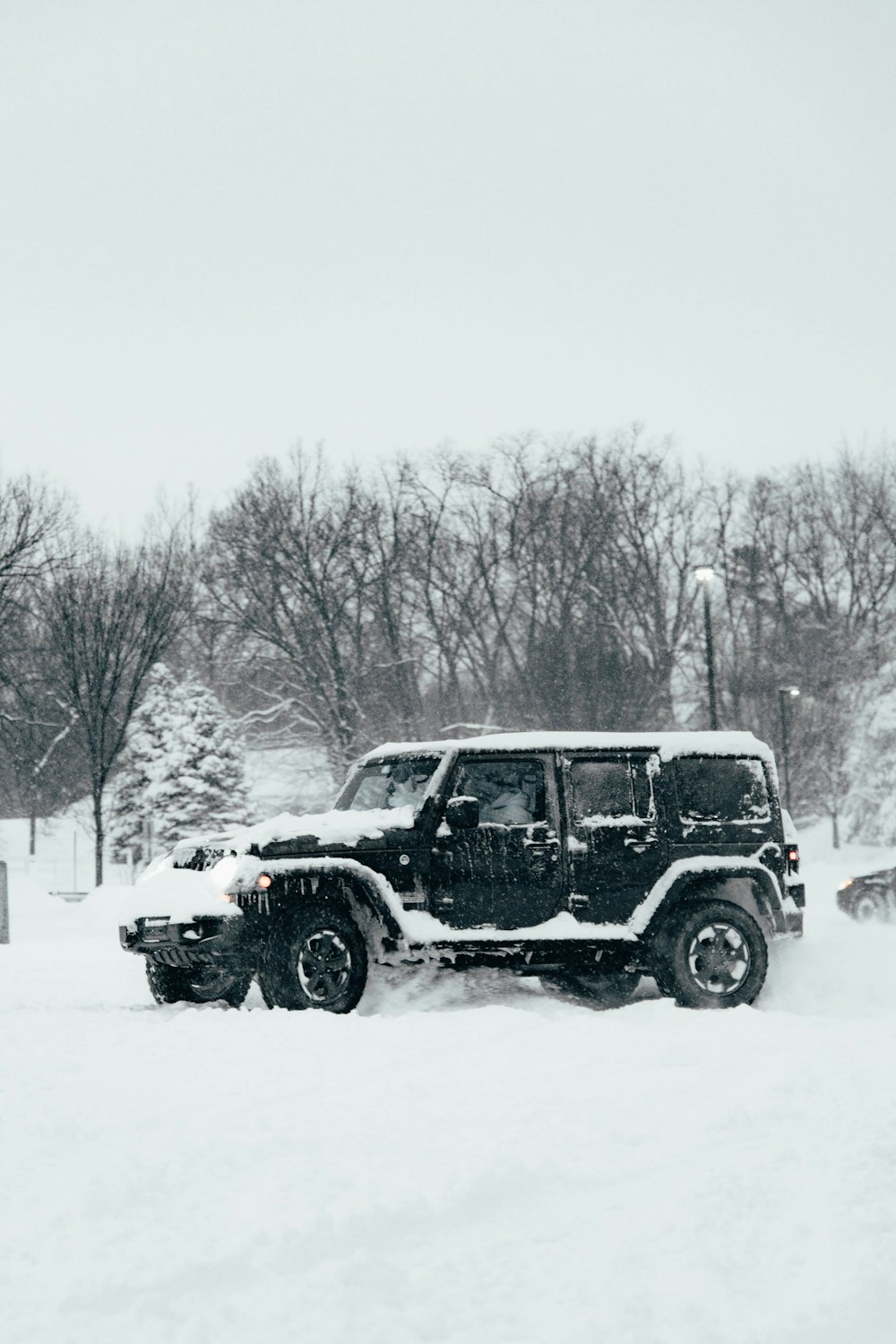 um jipe dirigindo através de um estacionamento coberto de neve