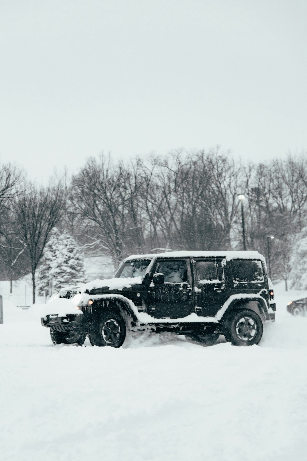 a jeep driving through a snow covered parking lot